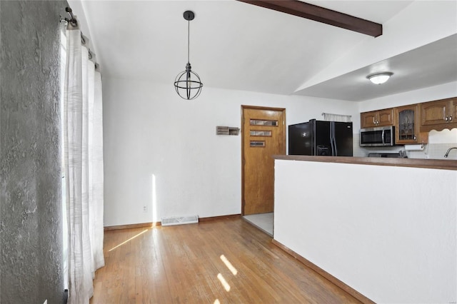 kitchen with visible vents, light wood-style flooring, lofted ceiling with beams, stainless steel microwave, and black fridge with ice dispenser