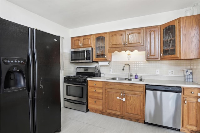 kitchen featuring brown cabinets, appliances with stainless steel finishes, light countertops, and a sink