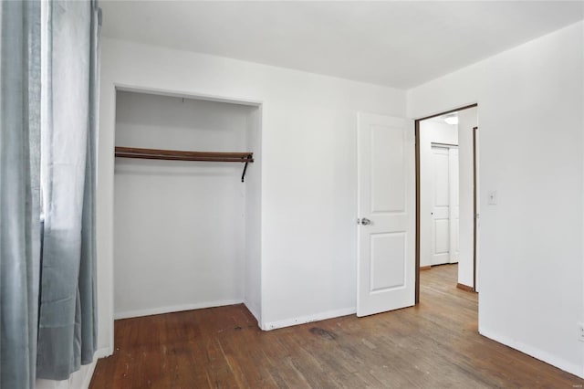 unfurnished bedroom with a closet, baseboards, and wood finished floors