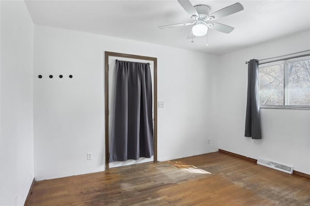 unfurnished room featuring visible vents, a ceiling fan, and wood finished floors