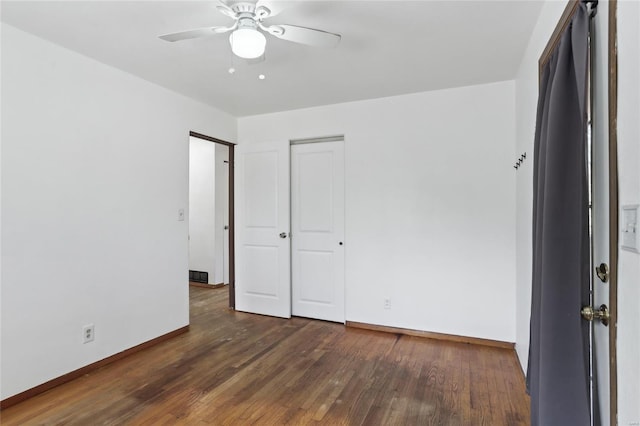 unfurnished bedroom with a closet, baseboards, wood finished floors, and a ceiling fan