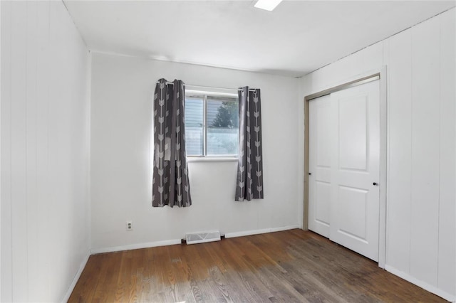 unfurnished bedroom with visible vents, baseboards, and wood finished floors