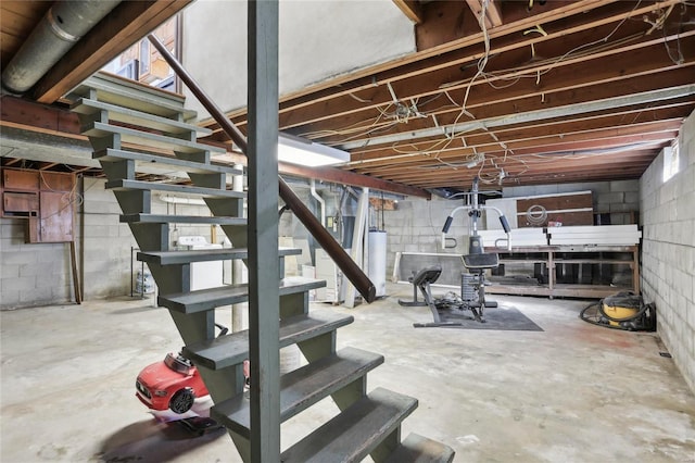 unfinished basement featuring stairs and water heater