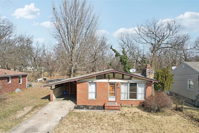 view of front facade featuring entry steps, concrete driveway, a front yard, an attached carport, and brick siding