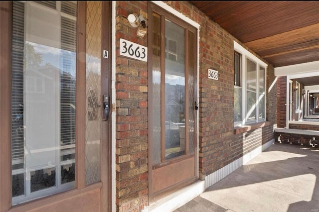 property entrance featuring a porch and brick siding