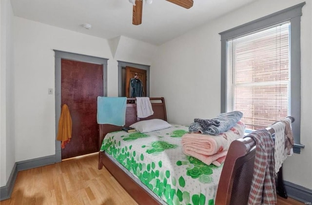 bedroom with a ceiling fan, wood finished floors, and baseboards