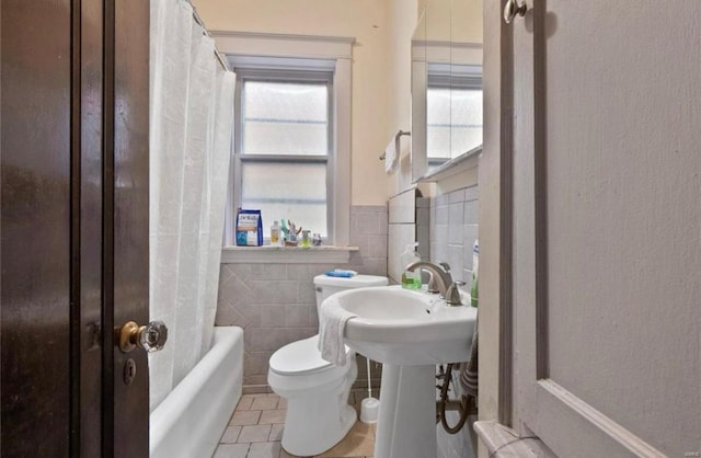 full bathroom featuring tile patterned floors, toilet, tile walls, and a healthy amount of sunlight