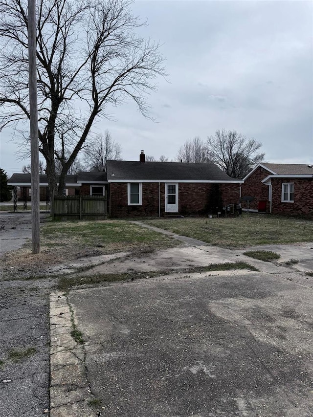 view of front of home featuring brick siding, a chimney, and a front lawn