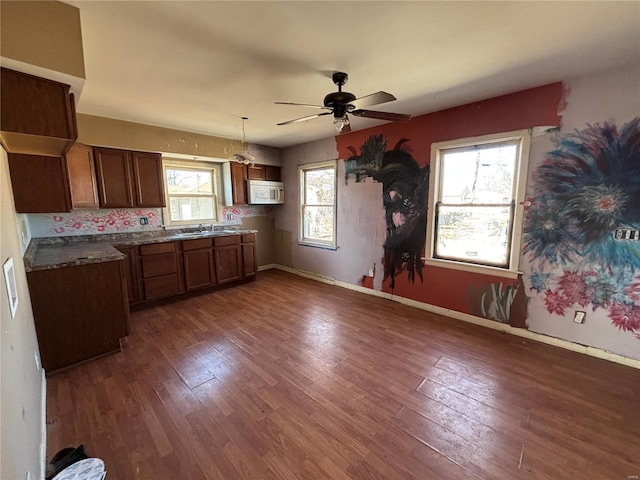 kitchen with white microwave, dark countertops, baseboards, ceiling fan, and dark wood-style flooring