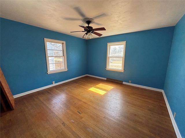 unfurnished room with a healthy amount of sunlight, ceiling fan, baseboards, and hardwood / wood-style floors