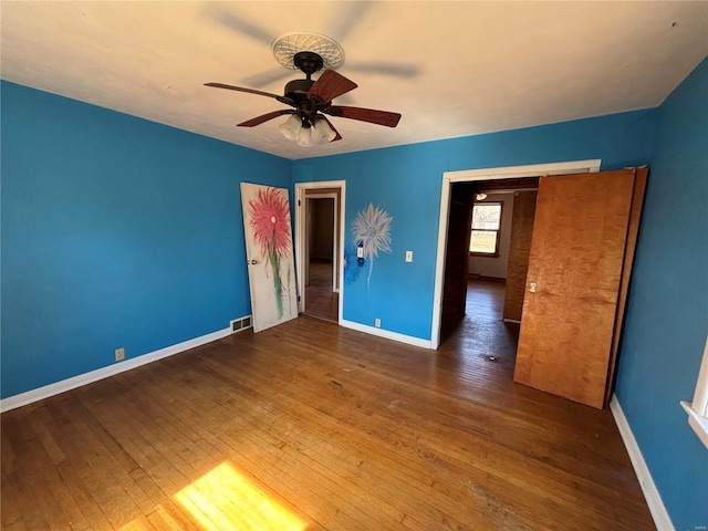 unfurnished room with visible vents, baseboards, wood-type flooring, and ceiling fan