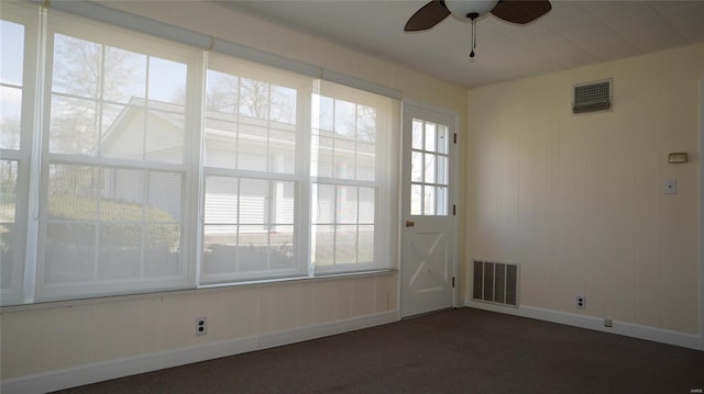 unfurnished room featuring visible vents, a wealth of natural light, a ceiling fan, and carpet flooring
