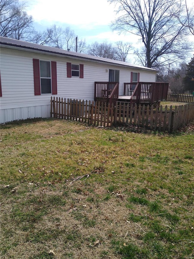 back of property featuring metal roof, a wooden deck, a yard, and fence