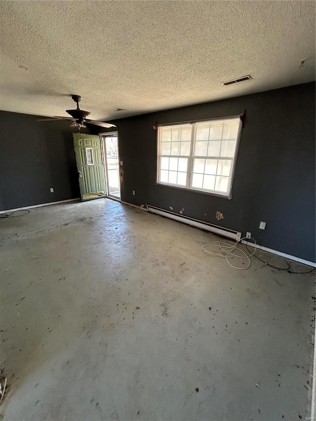 spare room featuring a baseboard heating unit, concrete flooring, a textured ceiling, and visible vents