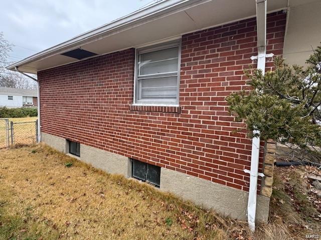 view of side of property featuring brick siding and fence