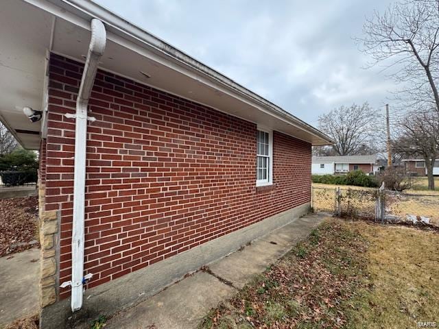 view of side of property with brick siding and fence