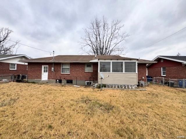 rear view of house featuring a yard, brick siding, and fence