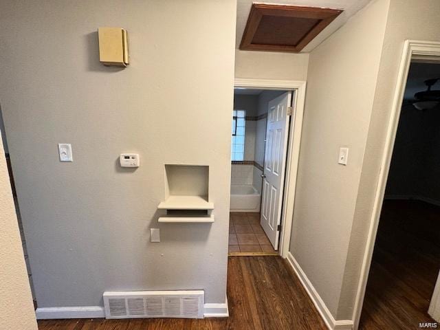 hallway with visible vents, attic access, baseboards, and dark wood-style flooring