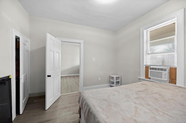 bedroom featuring cooling unit, wood finished floors, and baseboards