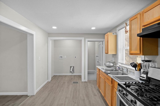 kitchen featuring visible vents, a sink, light wood-style floors, light countertops, and stainless steel range with gas stovetop