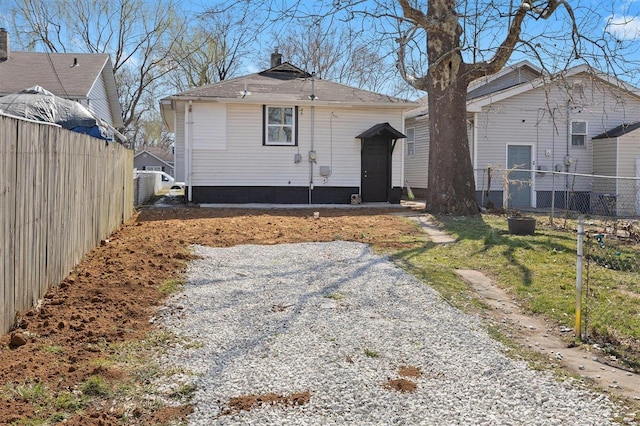 rear view of house featuring a chimney and fence