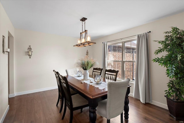 dining space with dark wood-style floors, a notable chandelier, and baseboards