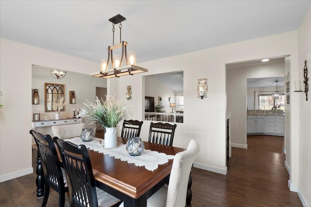 dining room with dark wood-style floors, a notable chandelier, and baseboards