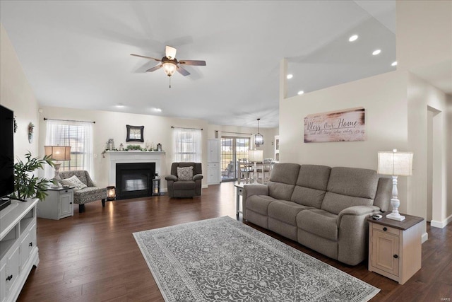 living room featuring dark wood-type flooring, a ceiling fan, and a healthy amount of sunlight