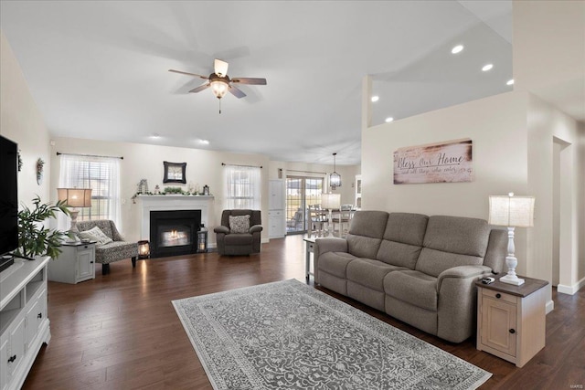 living room featuring dark wood-style floors, a fireplace with flush hearth, a healthy amount of sunlight, and ceiling fan