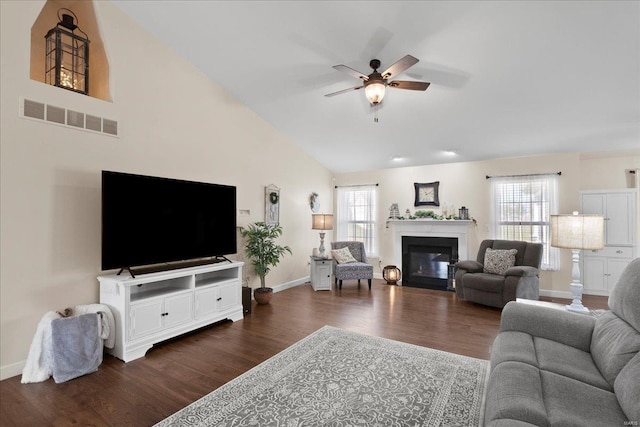 living room with a wealth of natural light, visible vents, a ceiling fan, and dark wood-style flooring