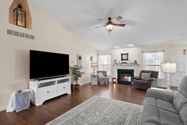 living room with visible vents, a healthy amount of sunlight, dark wood-style flooring, and a ceiling fan