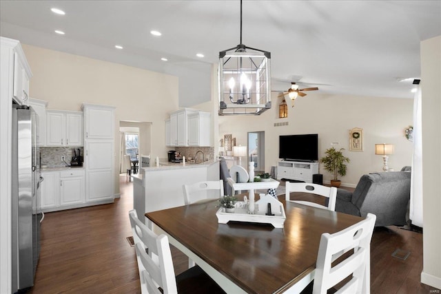 dining space featuring dark wood-style floors, recessed lighting, ceiling fan with notable chandelier, and high vaulted ceiling