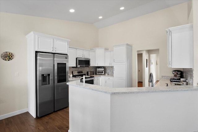 kitchen featuring dark wood-type flooring, tasteful backsplash, white cabinetry, appliances with stainless steel finishes, and a peninsula