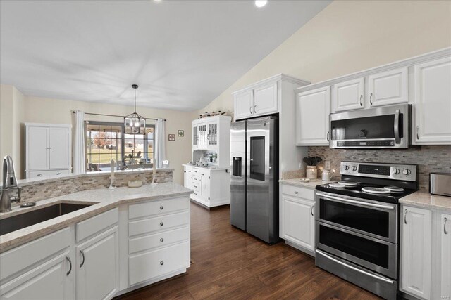 kitchen featuring backsplash, vaulted ceiling, appliances with stainless steel finishes, white cabinets, and a sink