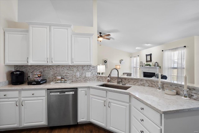 kitchen with tasteful backsplash, stainless steel dishwasher, white cabinetry, a ceiling fan, and a sink