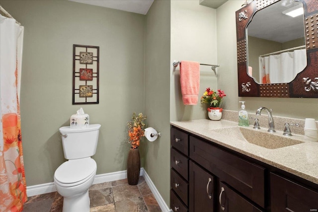 bathroom featuring toilet, vanity, and baseboards