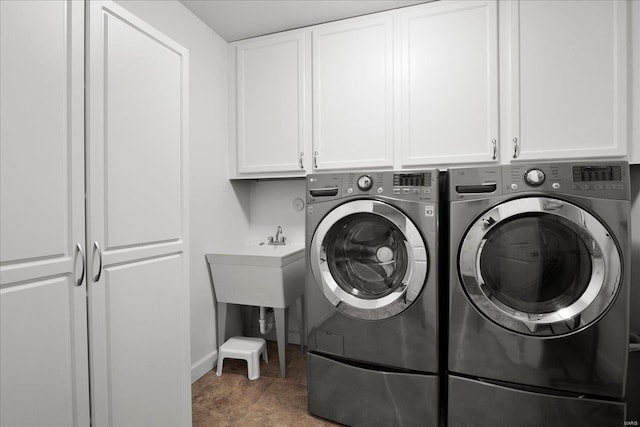 clothes washing area featuring washer and clothes dryer, cabinet space, and baseboards