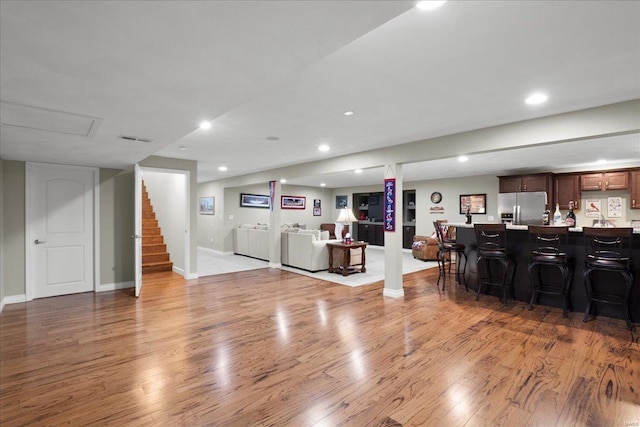 living area featuring stairway, bar area, wood finished floors, and recessed lighting