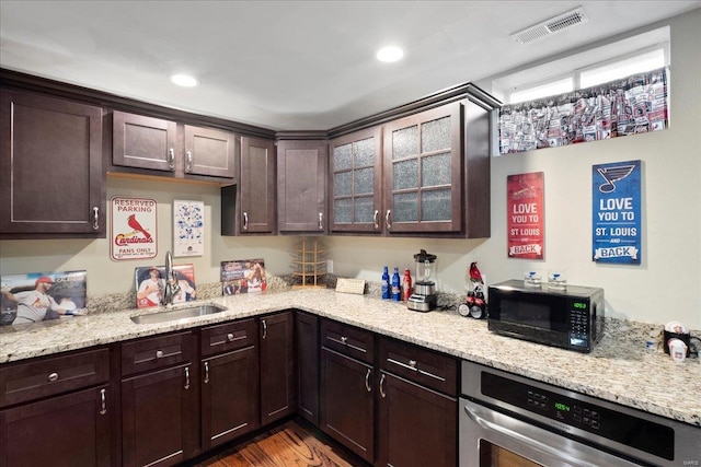 kitchen featuring dark brown cabinets, visible vents, black microwave, and a sink