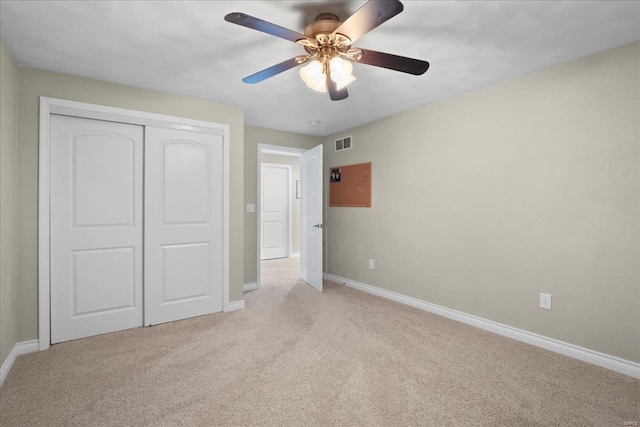 unfurnished bedroom with visible vents, baseboards, light colored carpet, a closet, and a ceiling fan