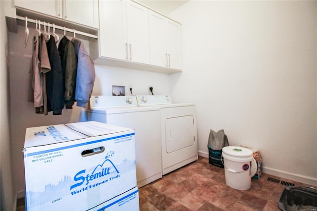 clothes washing area with separate washer and dryer, baseboards, visible vents, and cabinet space
