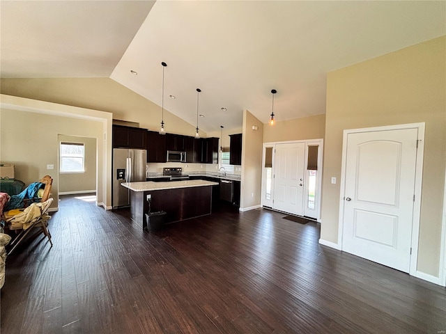 kitchen featuring a kitchen island, appliances with stainless steel finishes, dark wood-style flooring, light countertops, and open floor plan