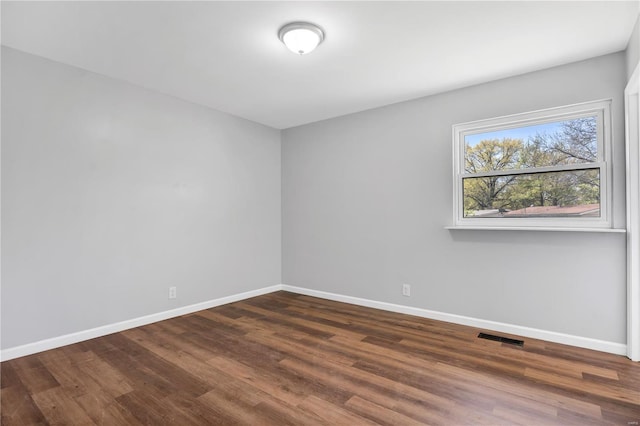 empty room with baseboards, wood finished floors, and visible vents