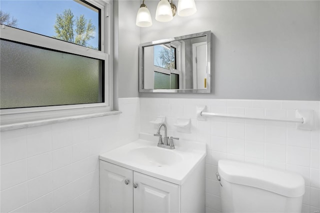 bathroom featuring tile walls, wainscoting, vanity, and toilet