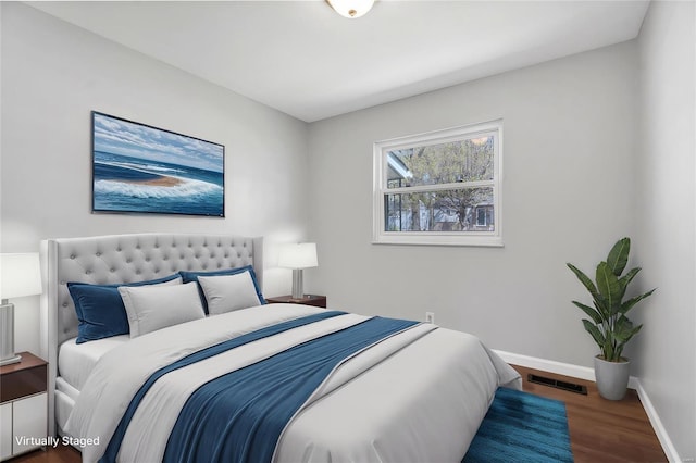 bedroom with baseboards, wood finished floors, and visible vents