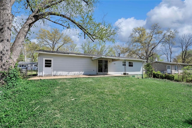rear view of property featuring fence, a lawn, and a patio area