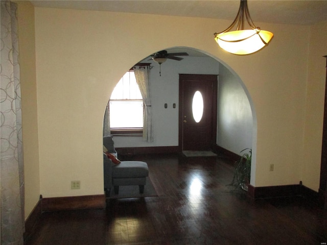 foyer featuring wood finished floors, a ceiling fan, baseboards, and arched walkways