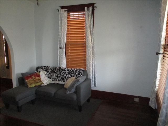 living room with wood finished floors, baseboards, and arched walkways