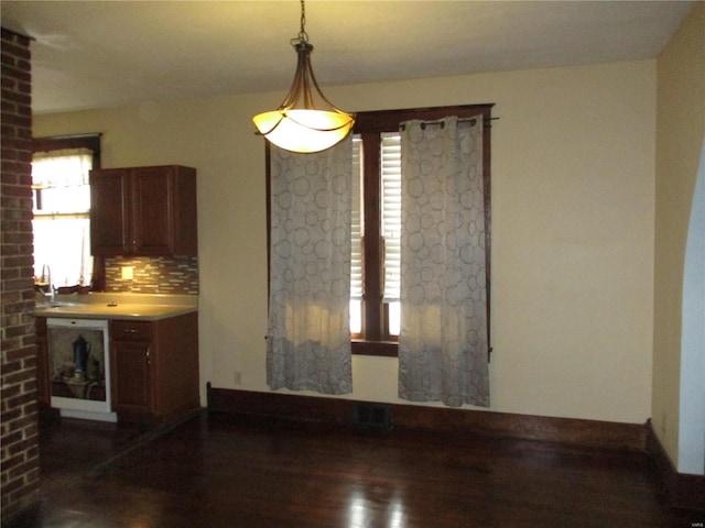 unfurnished dining area with dark wood-style floors and baseboards