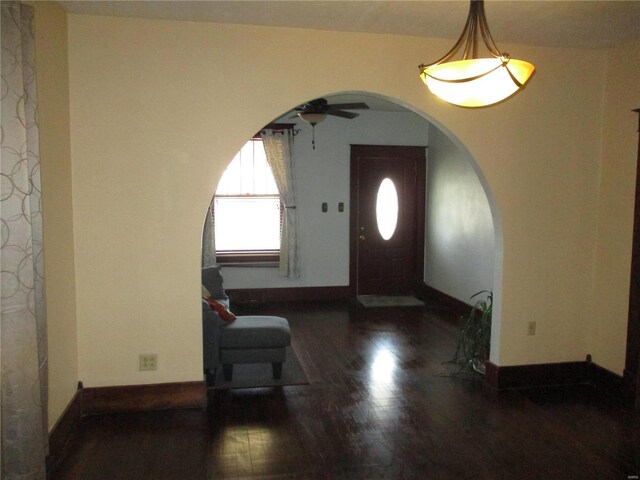 foyer entrance with arched walkways, wood finished floors, baseboards, and ceiling fan